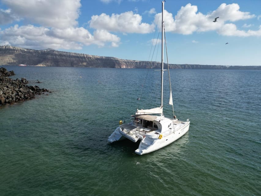 Santorini: Catamaran Cruise with Greek BBQ and Drinks - Red Beach and Santorini’s rust-coloured cliffs